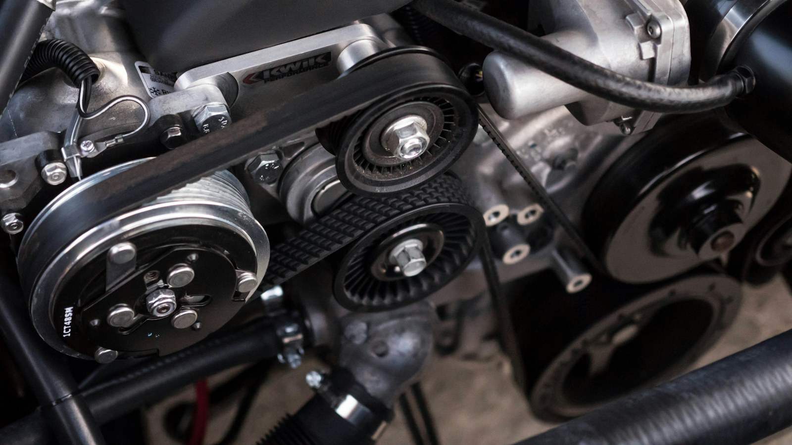 Detalhe de motor automotivo com correias e polias.